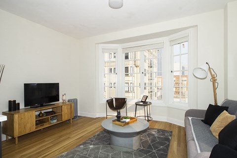A living room with a grey sofa and a wooden entertainment center.