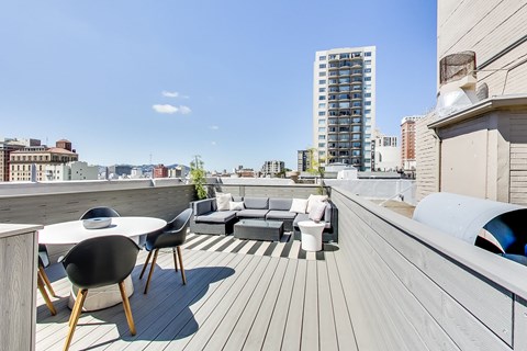 A wooden deck with a table and chairs overlooking a cityscape.