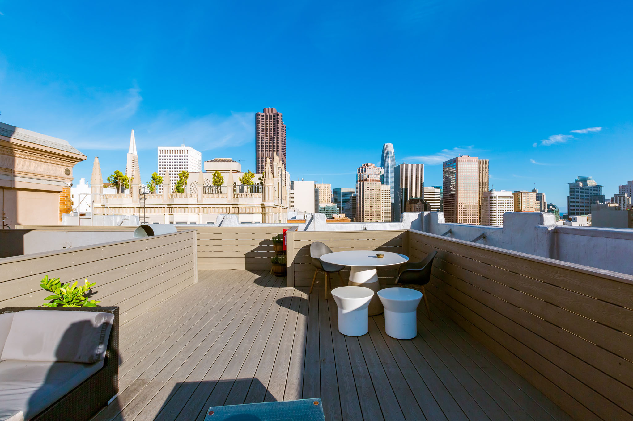 A rooftop patio with a table and chairs overlooking a city skyline.