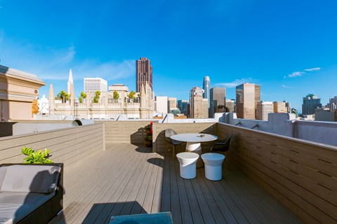 A rooftop patio with a table and chairs overlooking a city skyline.