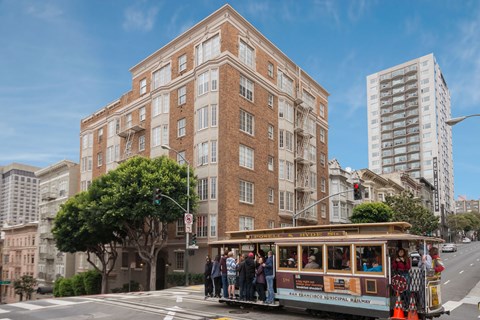 A trolley car is on a street in front of a brick building.