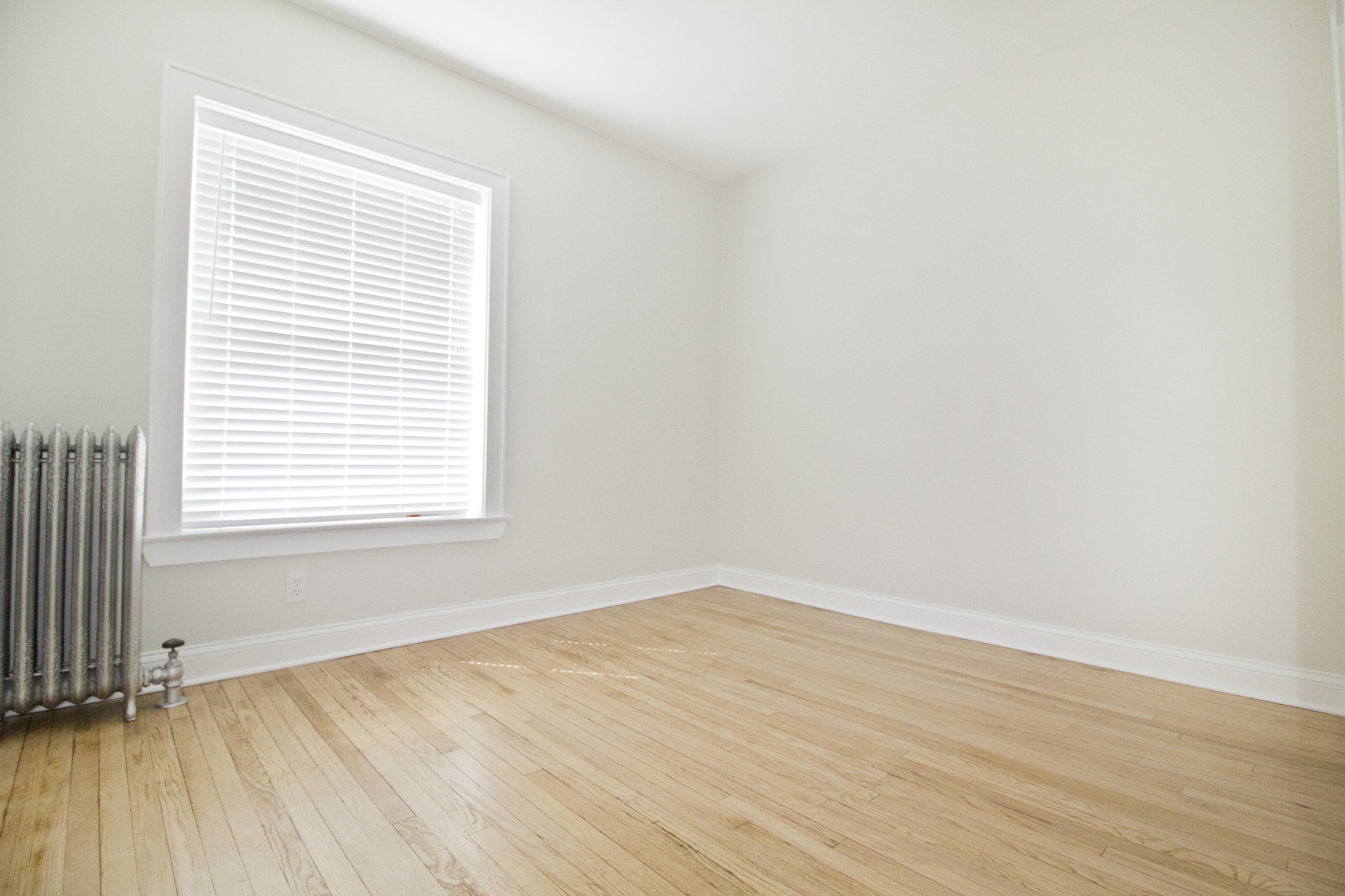 an empty room with wood floors and a window