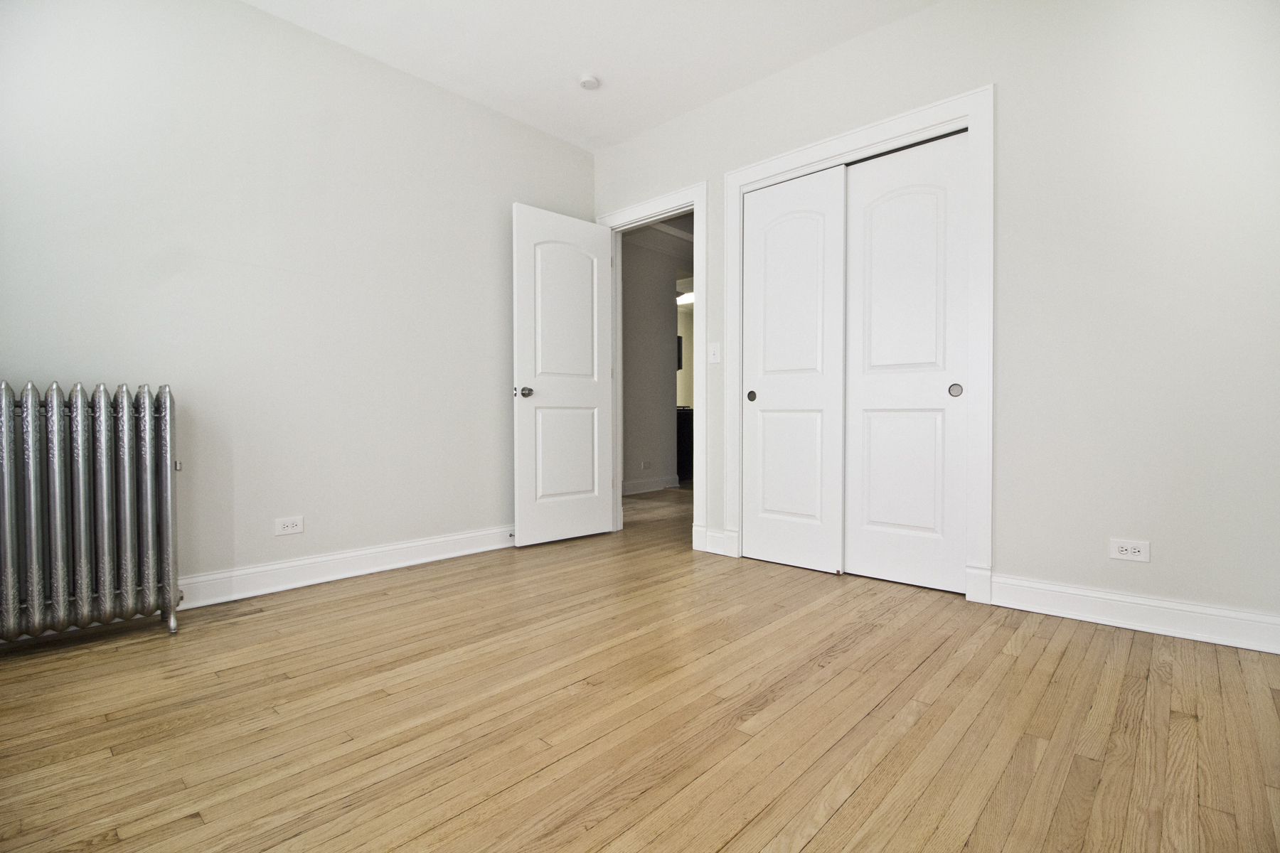 an empty room with white doors and a radiator