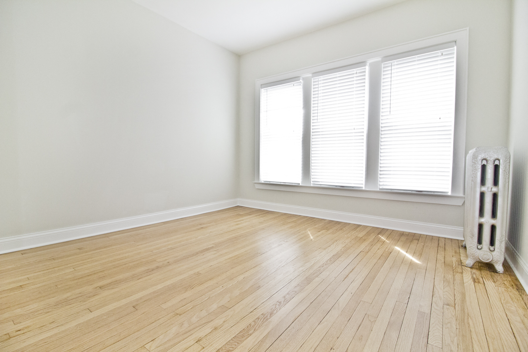 an empty room with white walls and wooden floors and a radiator