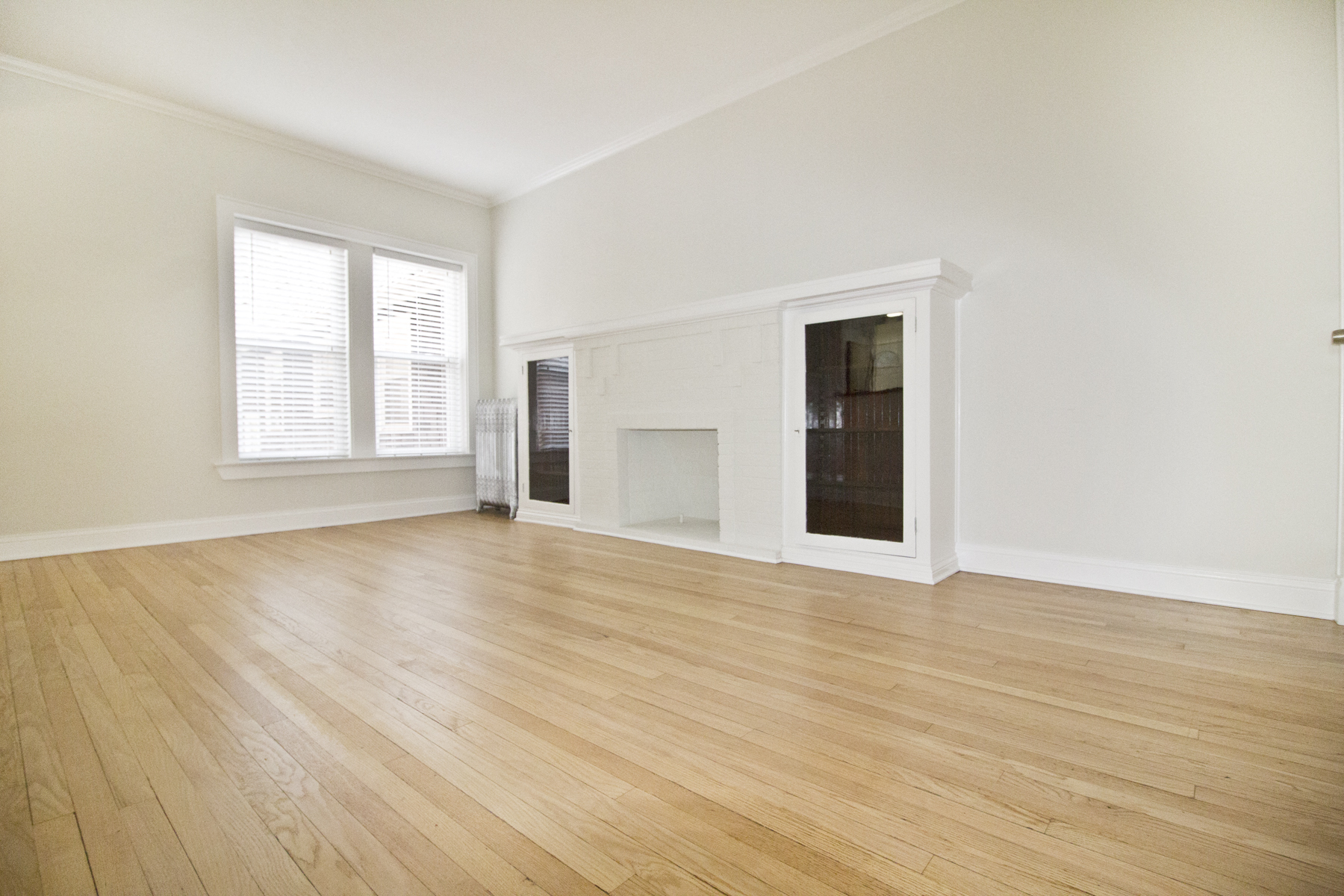 an empty living room with wood floors and a fireplace