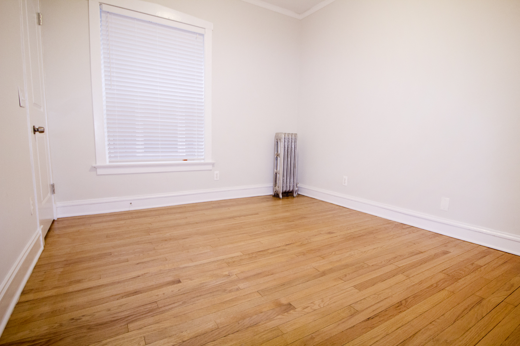 an empty room with wood floors and a window