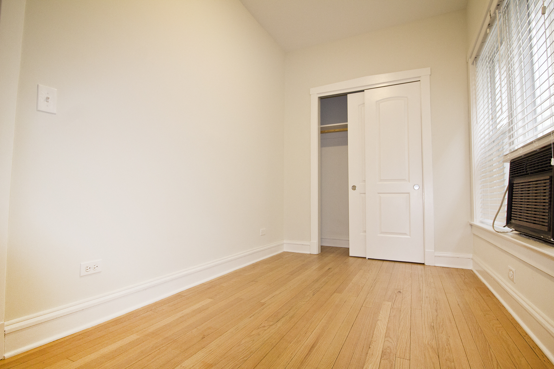 an empty living room with wood floors and a white door