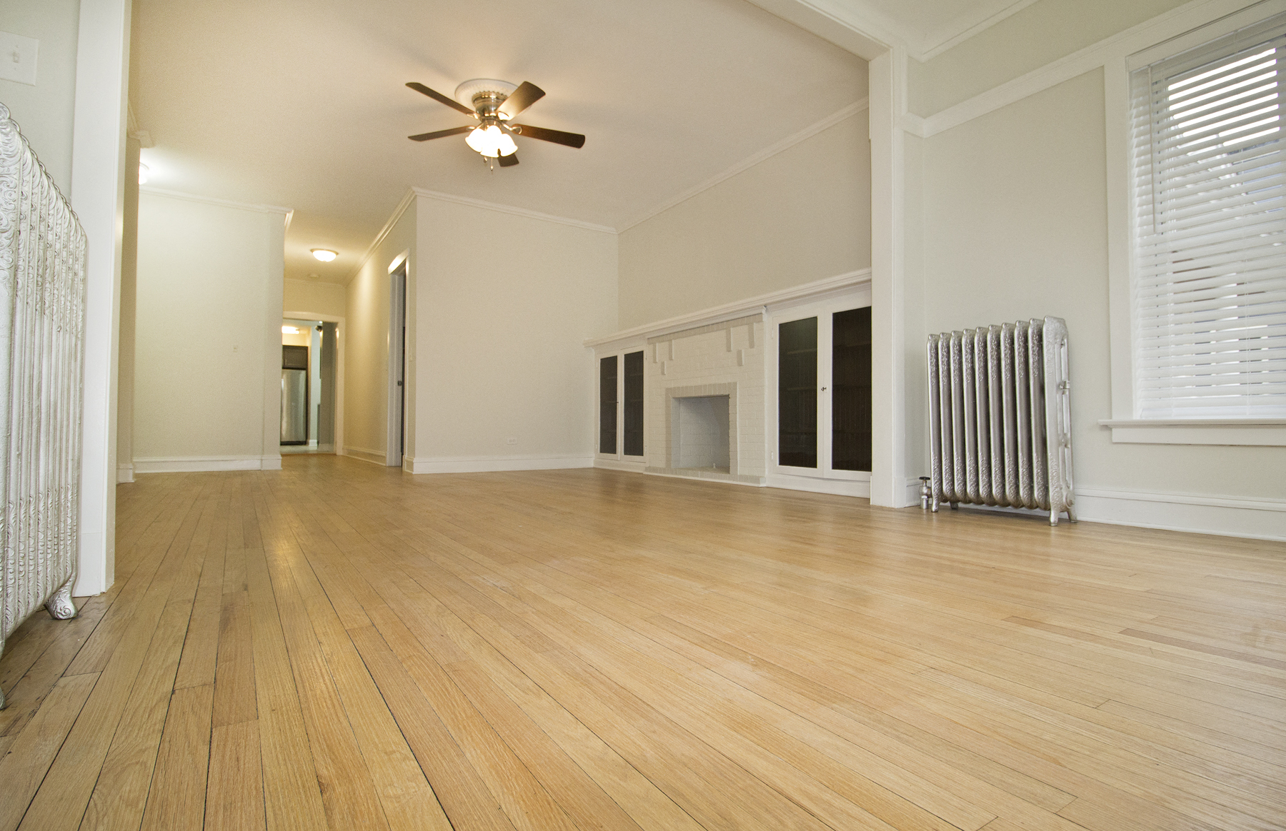 an empty living room with a ceiling fan and a fireplace