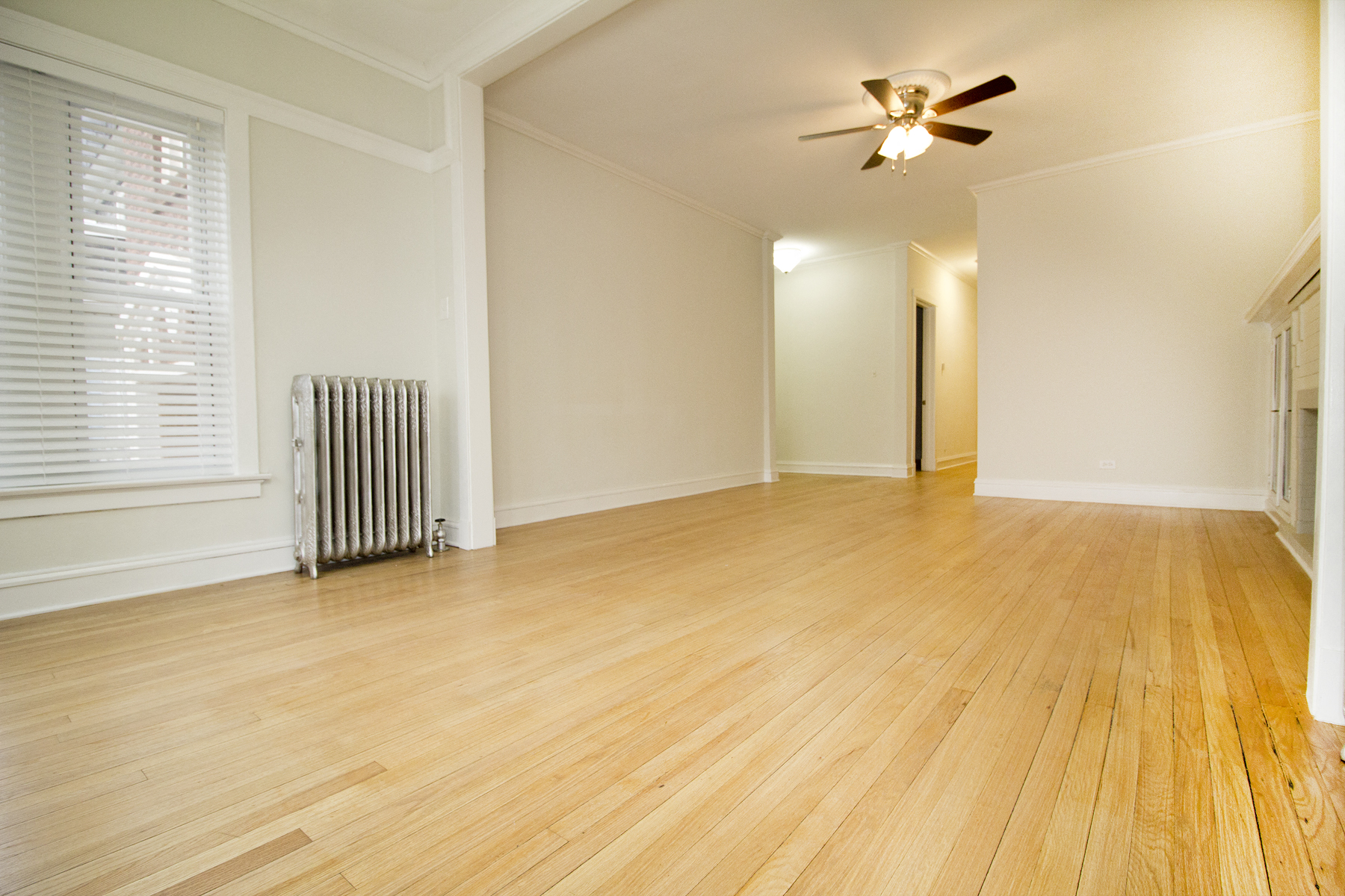 the living room and dining room with wood floors and a ceiling fan