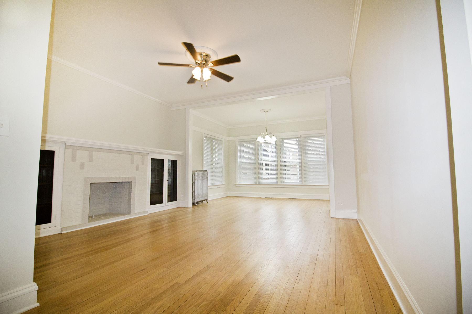 an empty living room with a ceiling fan and a fireplace