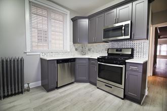a kitchen with gray cabinets and a stove and a microwave