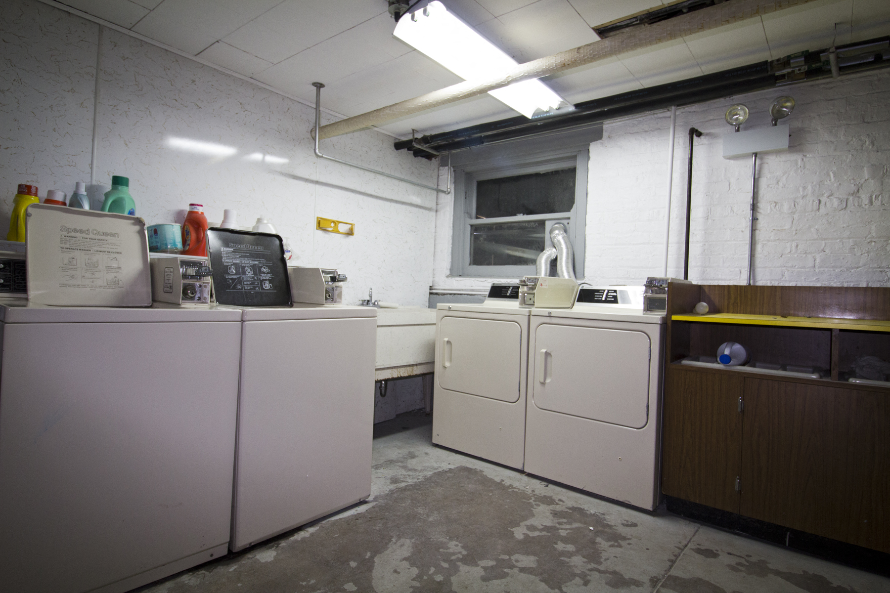an old laundry room with three washing machines and a window