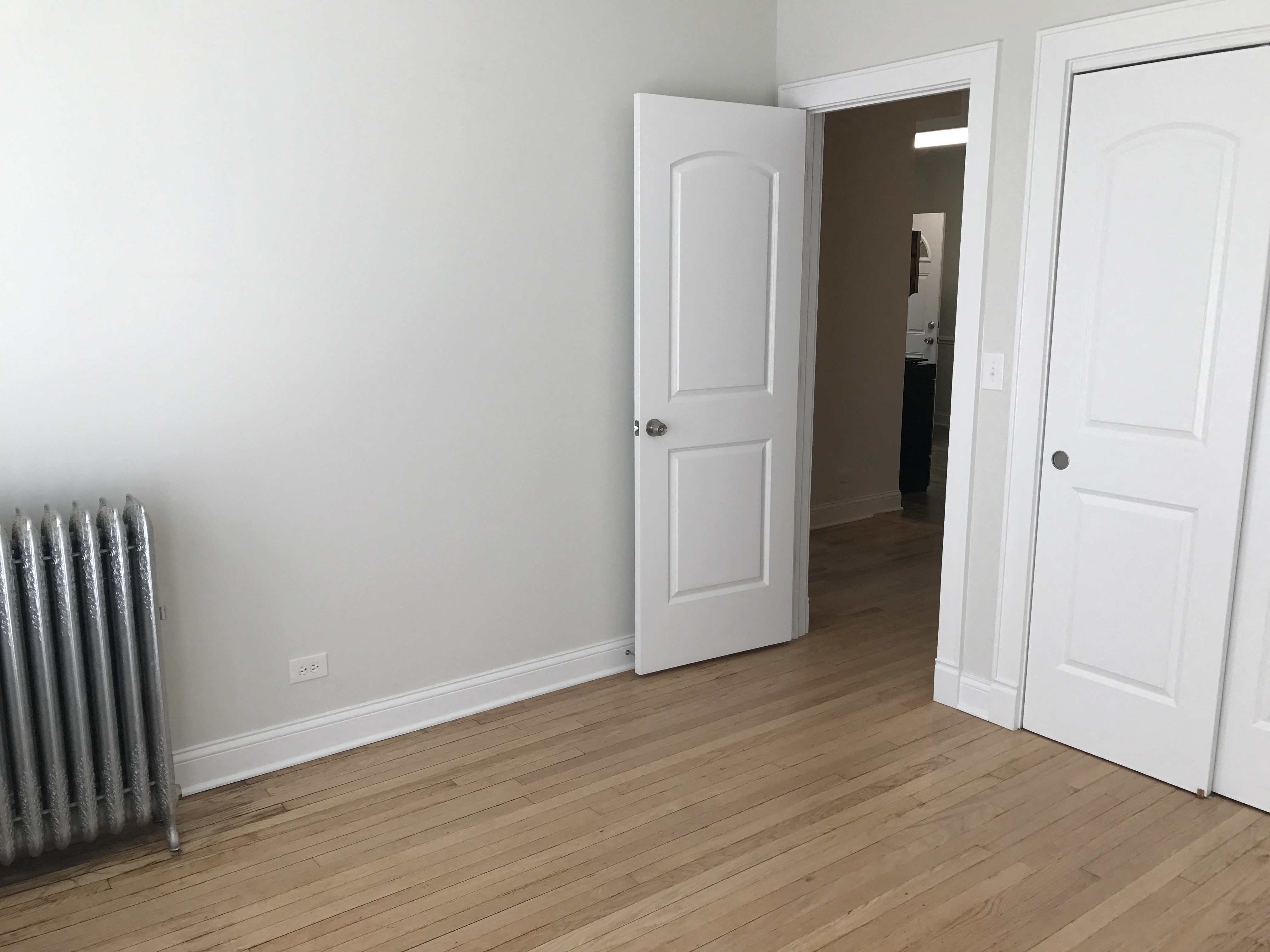 a room with two doors and a radiator and a closet