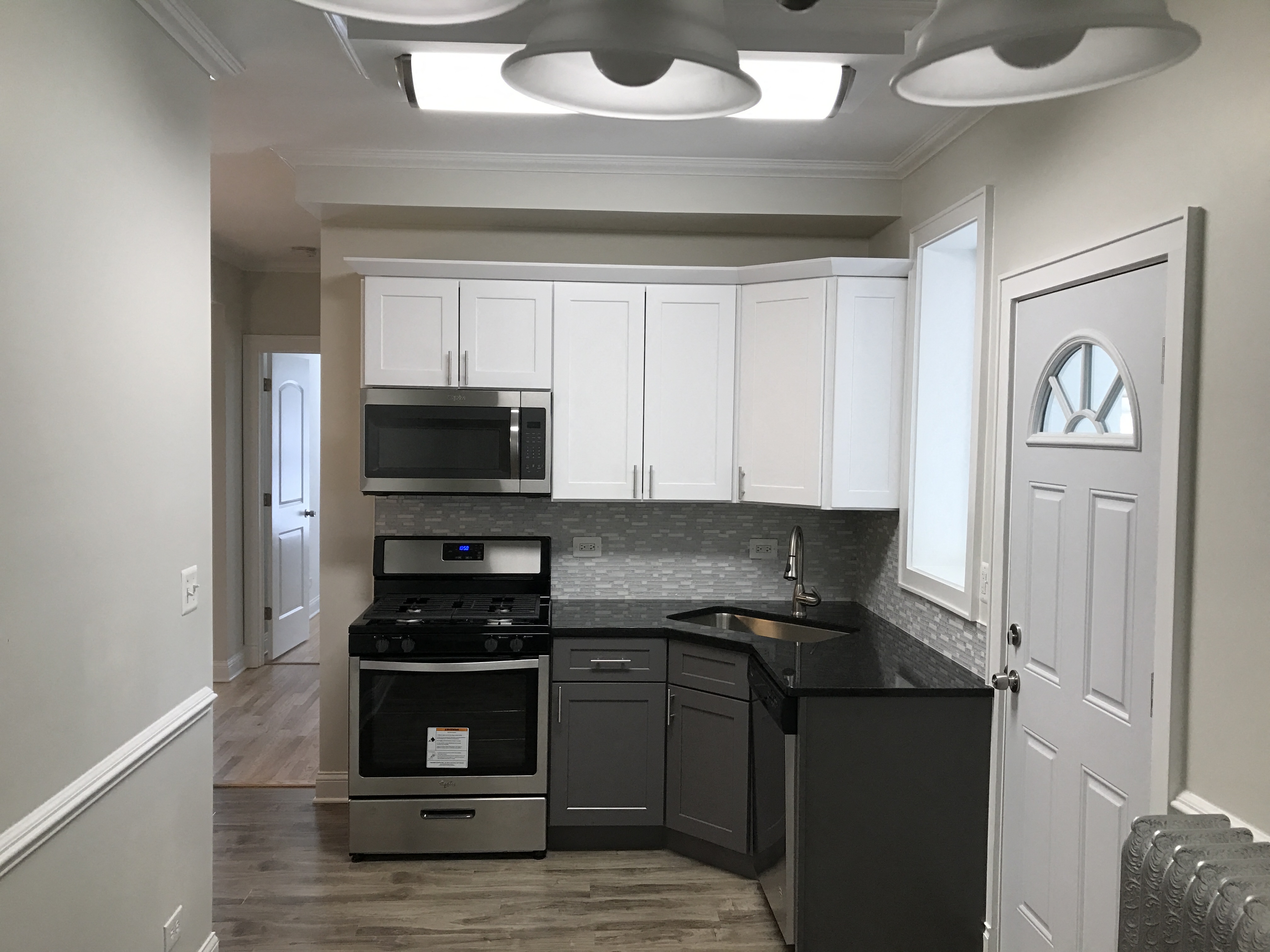 a kitchen with white cabinets and black counter tops and a stove and microwave