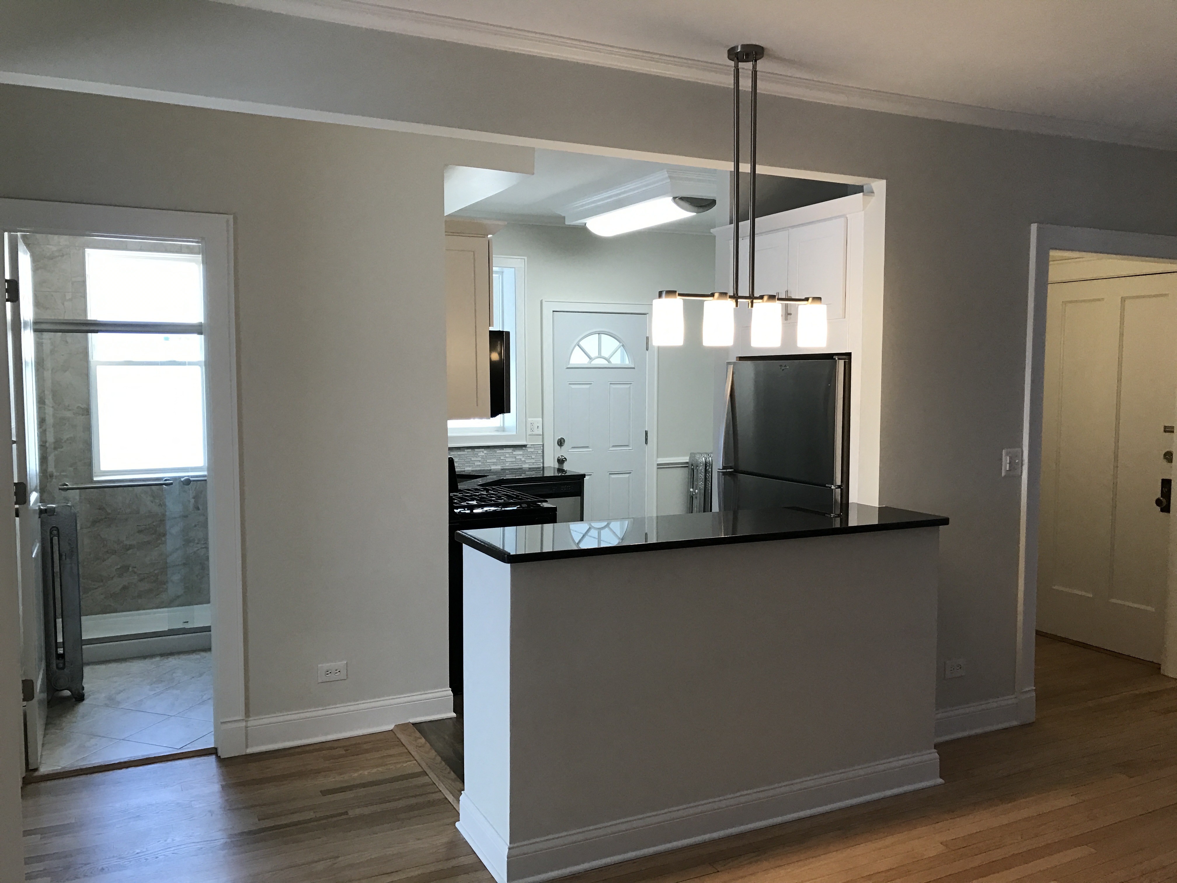 a kitchen with a island and a door into a living room