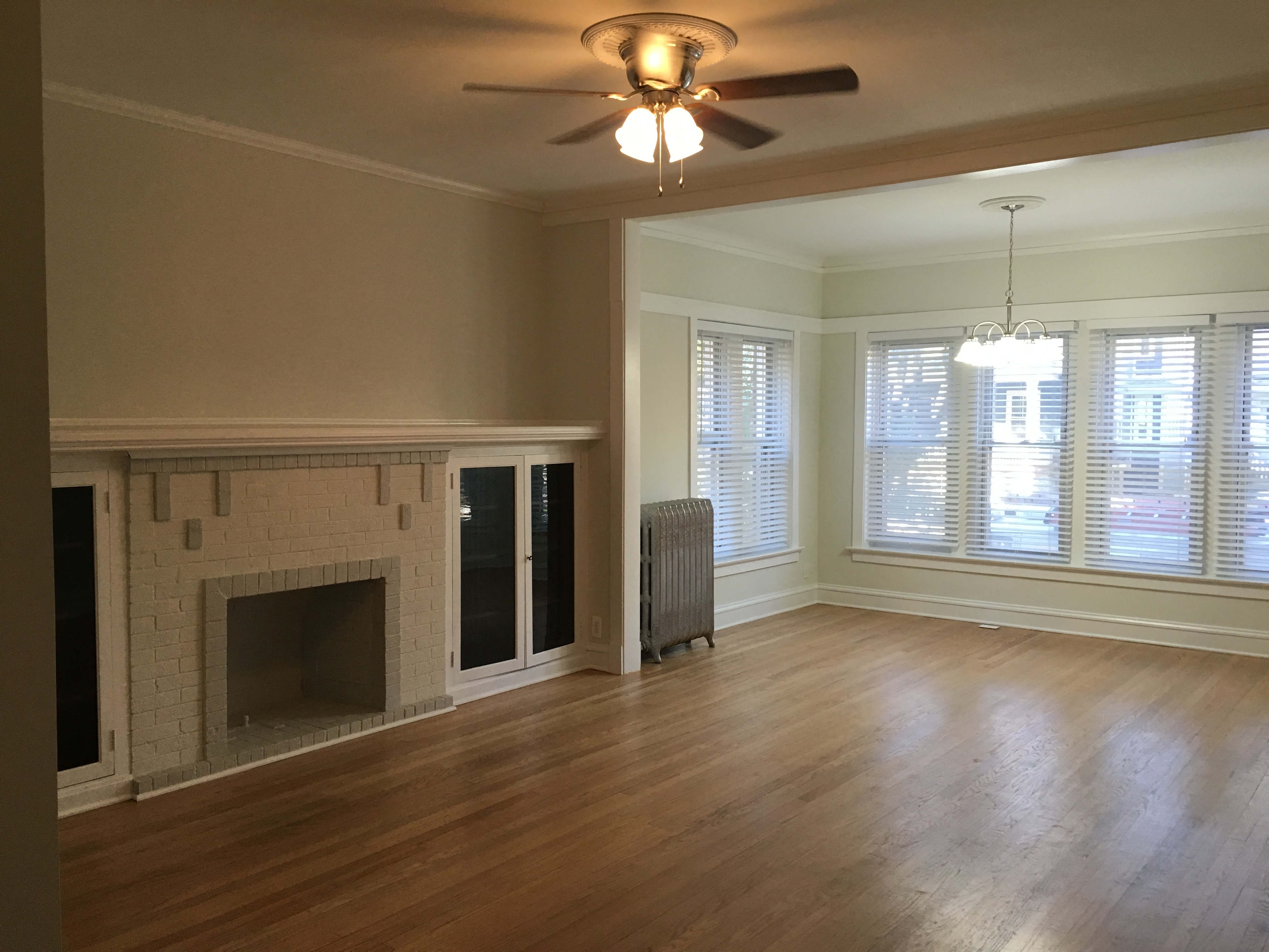 an empty living room with a fireplace and a ceiling fan