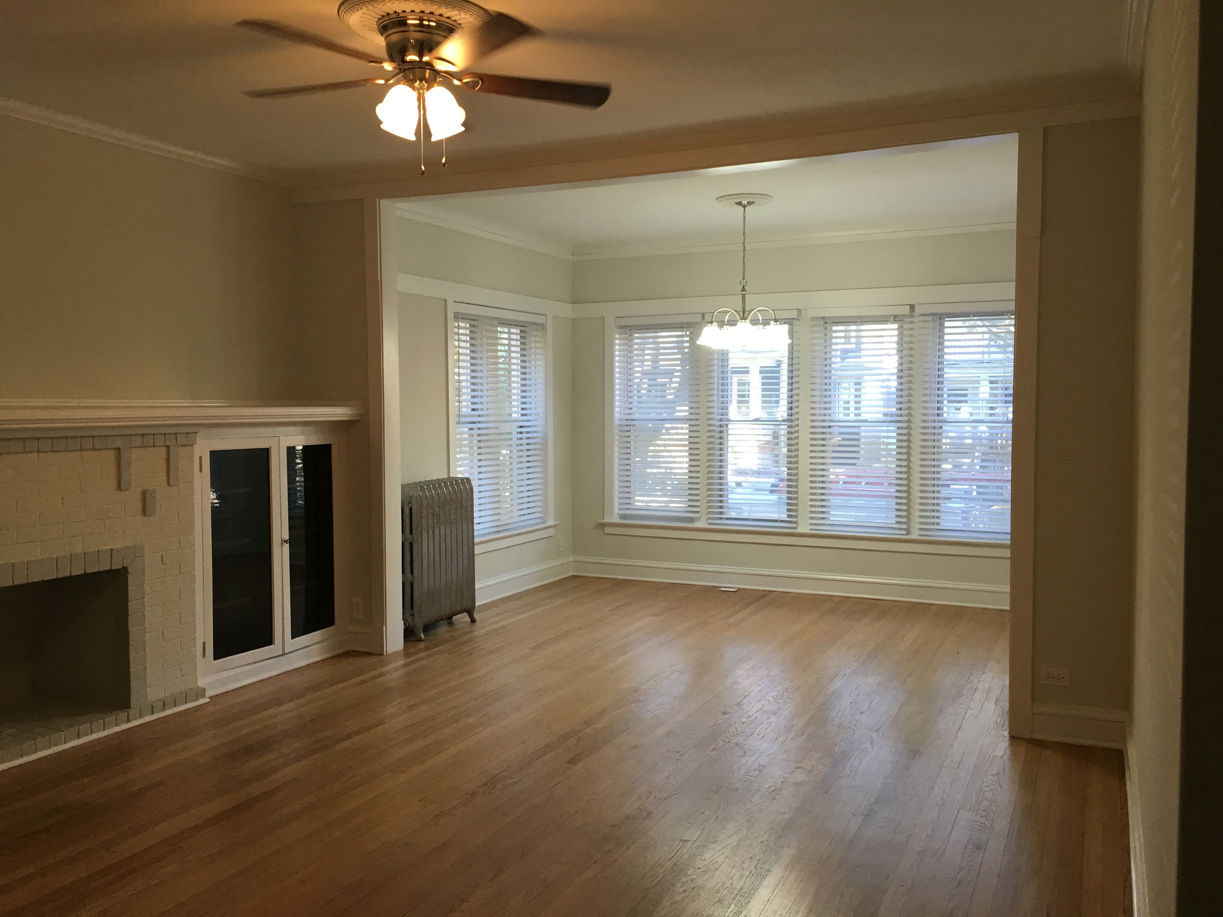 an empty living room with a fireplace and a ceiling fan