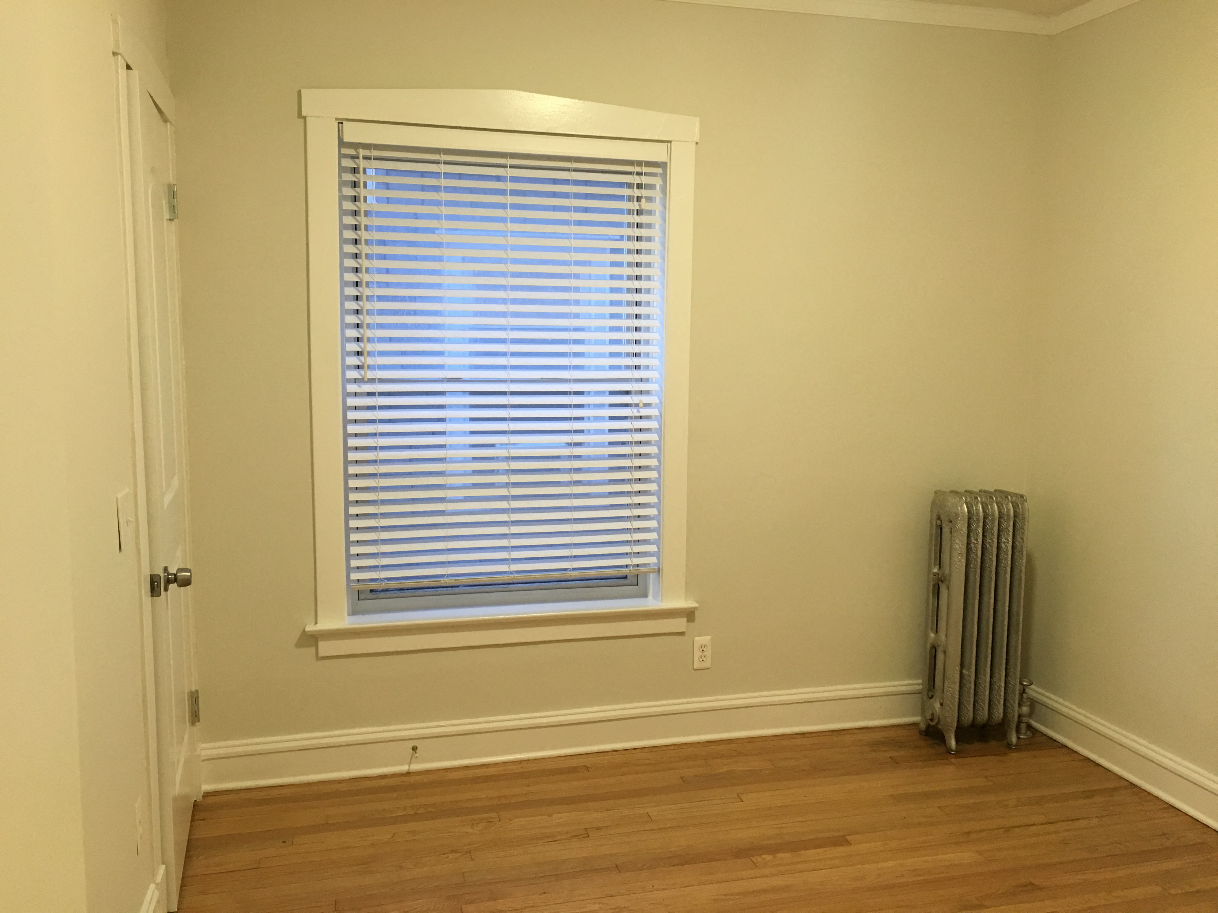 a room with a radiator and a window with blinds