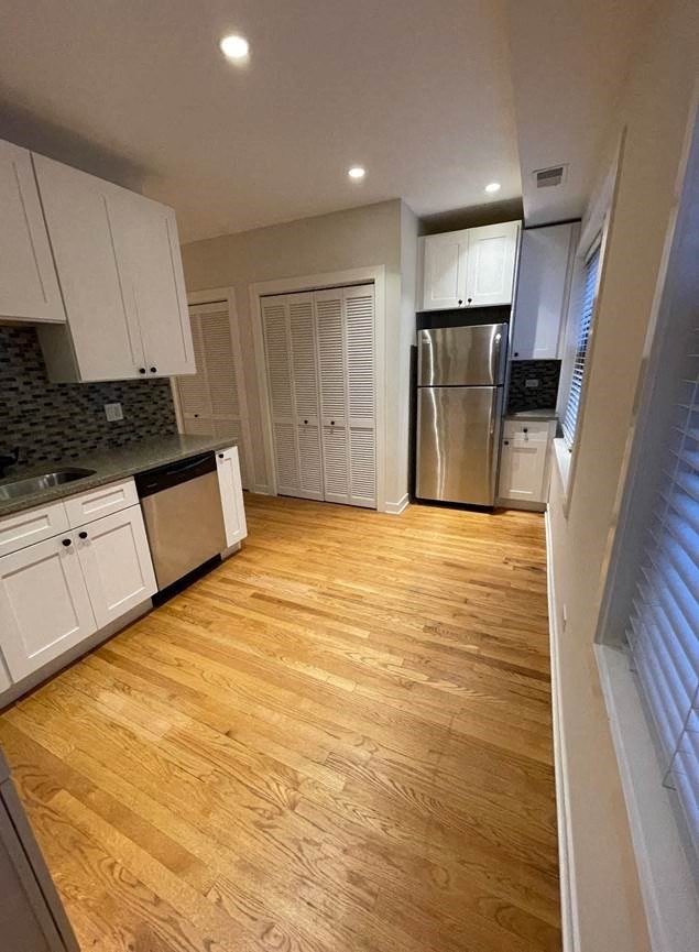 a kitchen with white cabinets and a stainless steel refrigerator