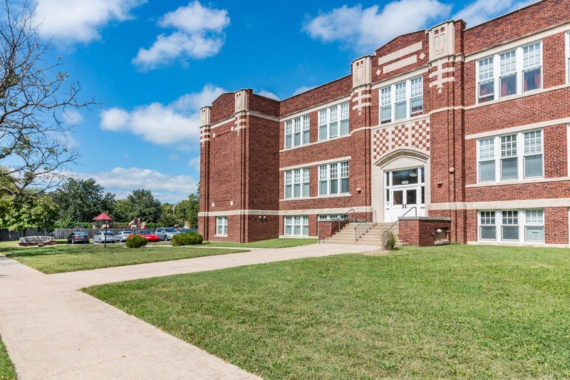 a large brick building with a lawn and sidewalk in front of it
