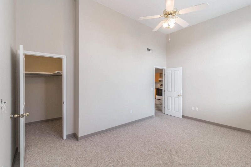 an empty bedroom with a closet and a ceiling fan