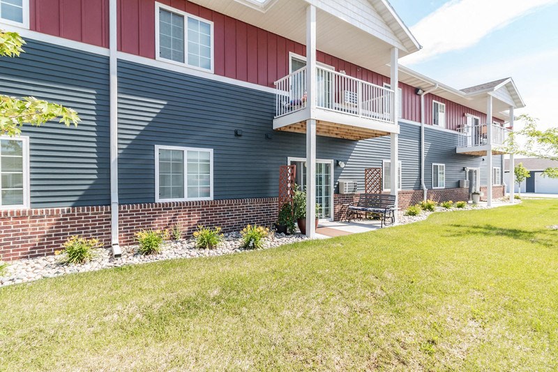 the front of a blue house with a porch and a lawn