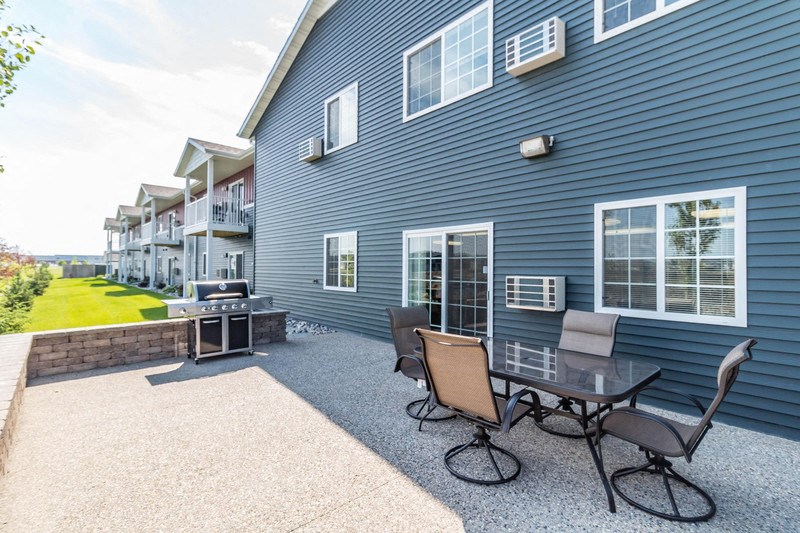 a patio with a table and chairs in front of a house