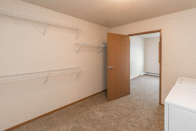 an empty laundry room with a closet and a white washer and dryer