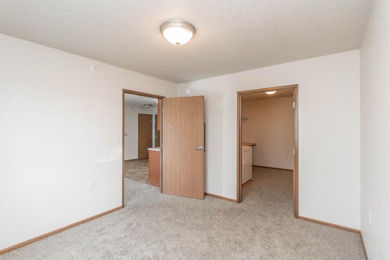 an empty living room with a door to a bathroom and a closet