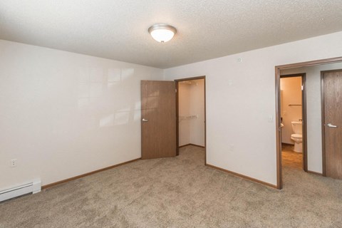 an empty bedroom with a door to a bathroom and a closet