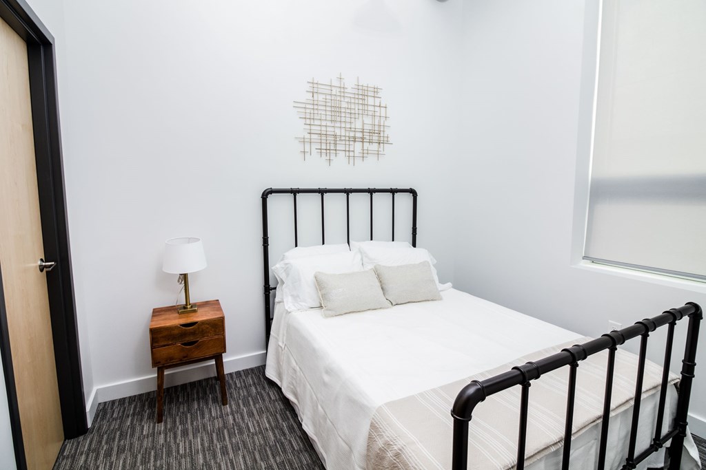 a bedroom with a white bed and a black metal bed frame