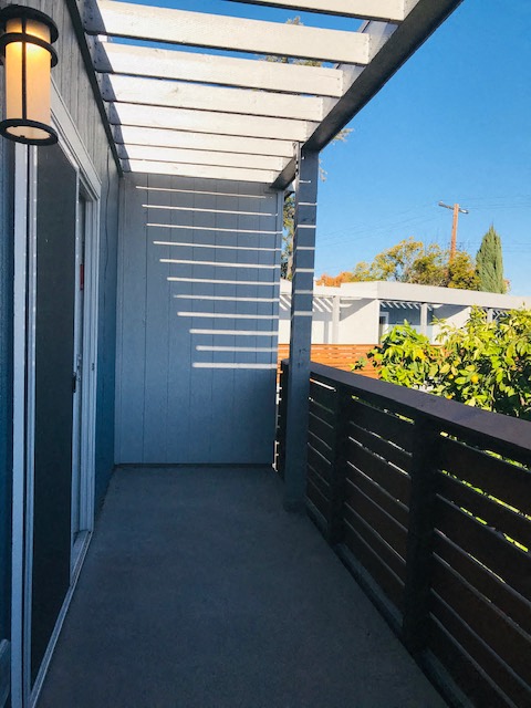 a long porch with a black fence and a blue sky