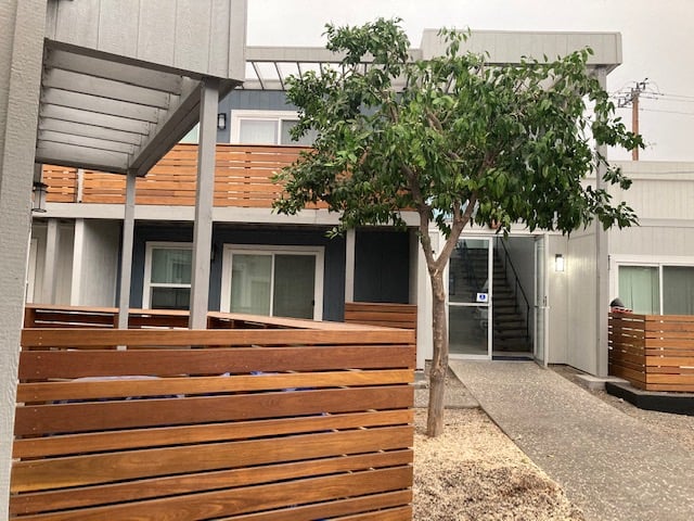 a building with a wooden fence and a tree in front of it