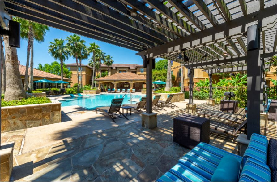 a large swimming pool with blue chairs and a covered patio