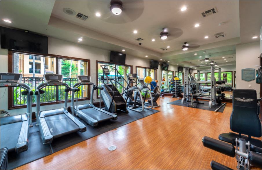 a gym with cardio equipment and windows in a building