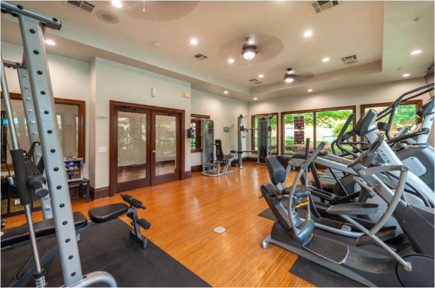 a gym with cardio machines and weights on a wooden floor