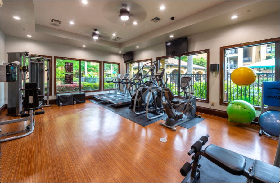 a gym with cardio machines and weights on a wooden floor