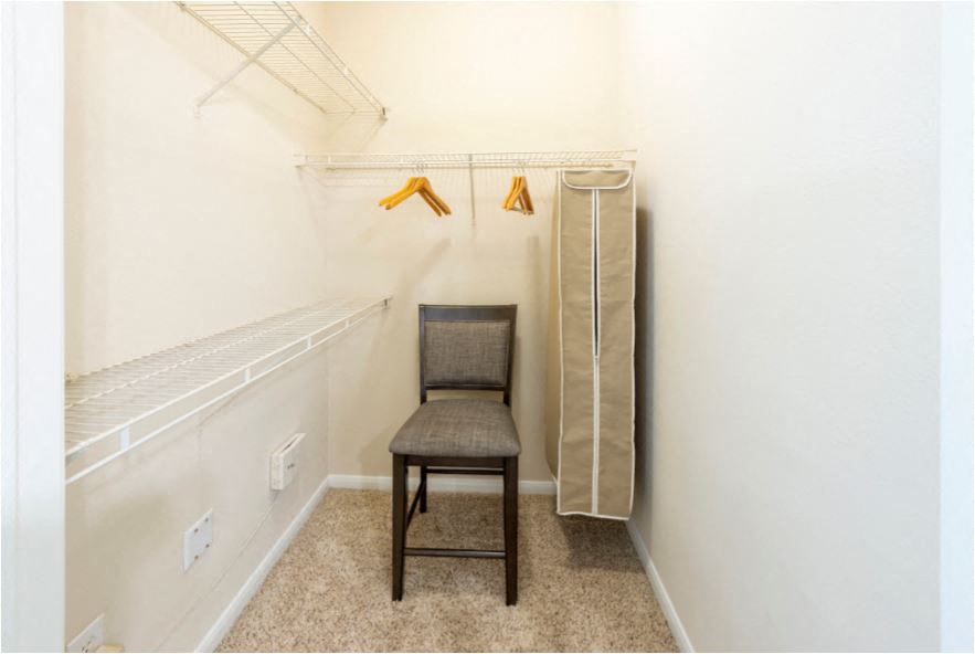 a walk in closet with a chair and a closet organizer