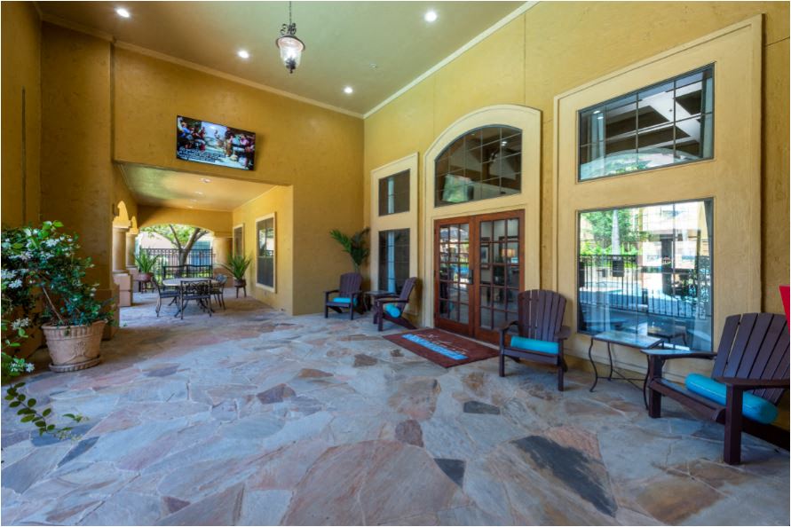 a large patio with a door and chairs and a tv