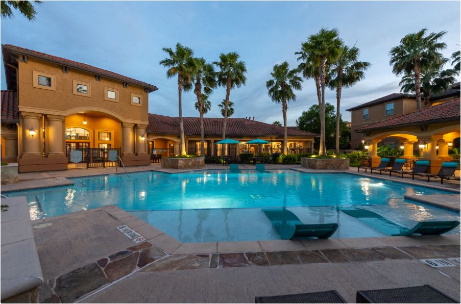 a large swimming pool in front of a resort with palm trees