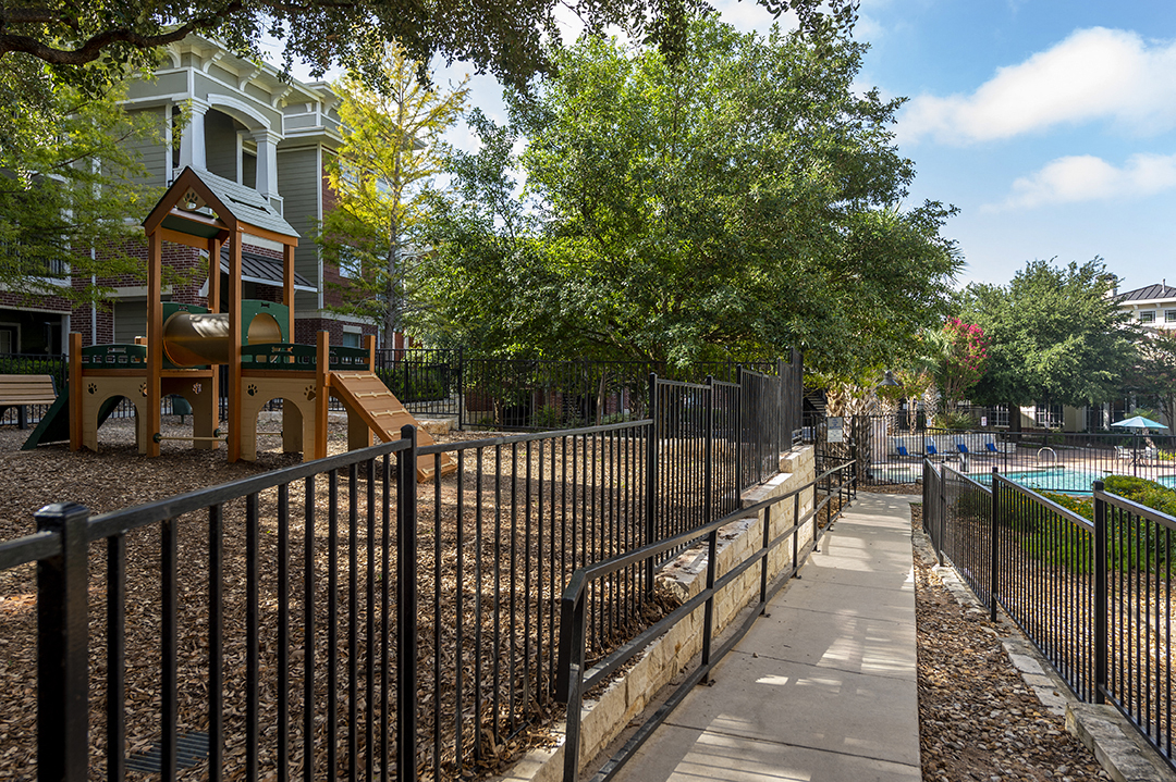 a fenced in park with a playground and a pool