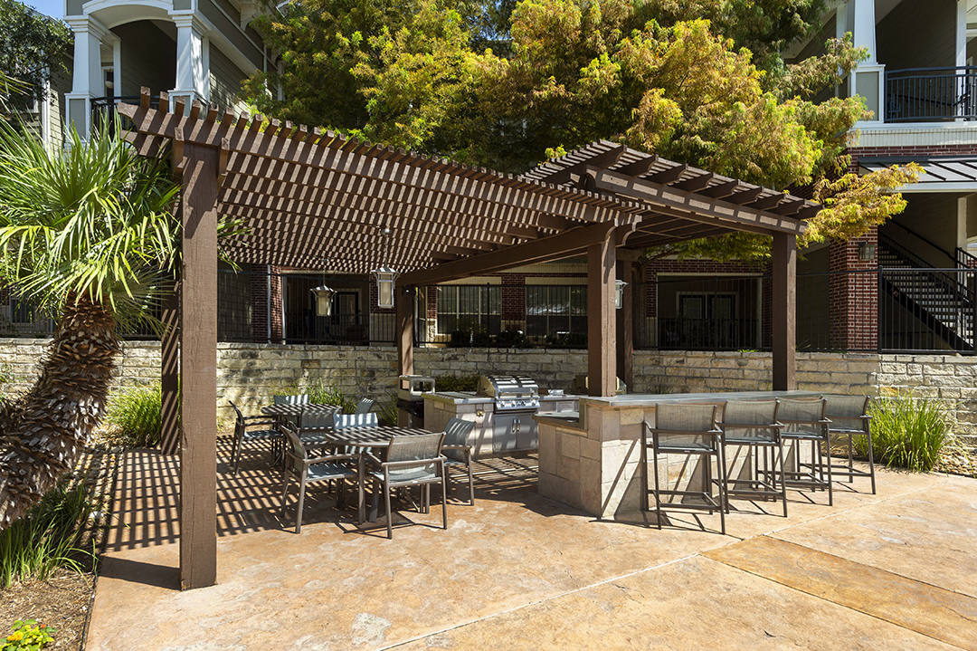 a patio with tables and chairs and a wooden pergola