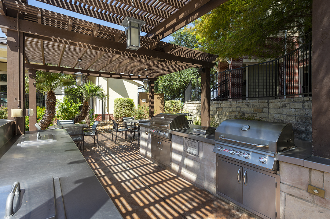 a large outdoor kitchen with stainless steel appliances and a pergola