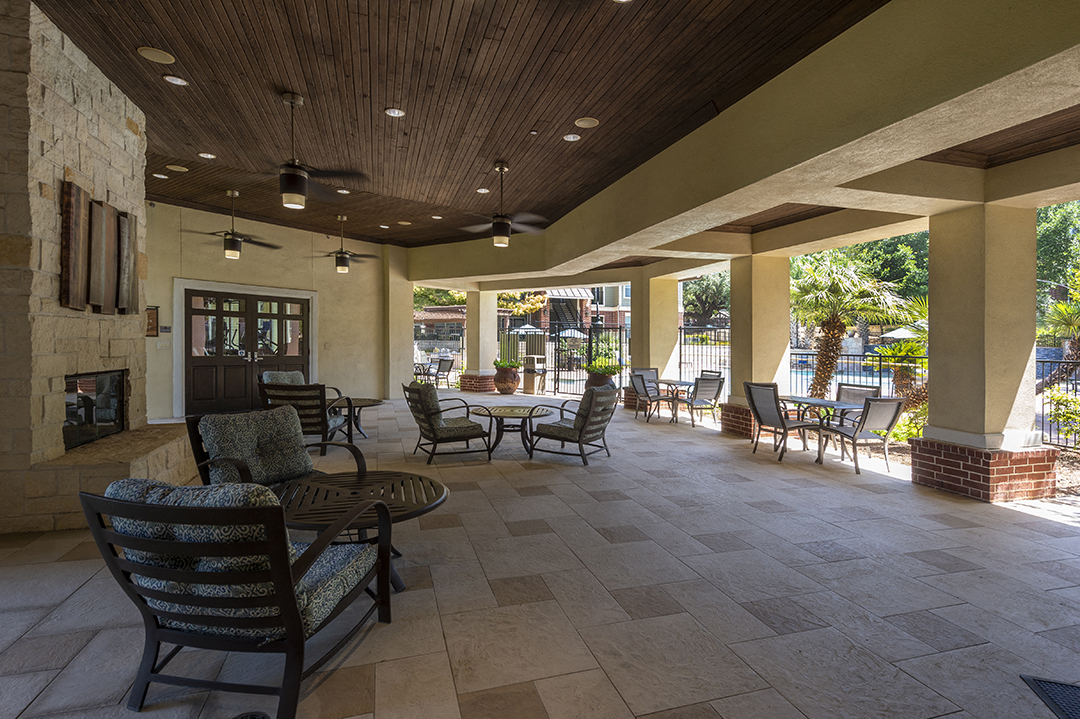 a covered patio with chairs and tables and a fireplace