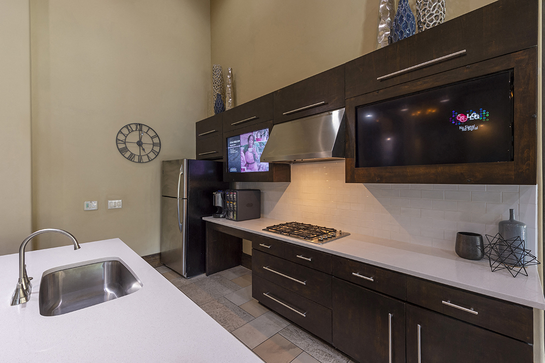 a kitchen with a sink and a refrigerator and a tv