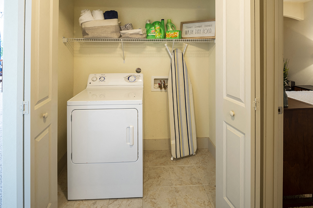a white washer and dryer in a small laundry room with a shelf above
