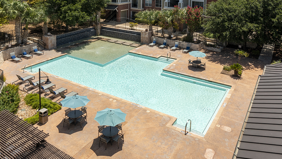 an aerial view of a swimming pool with tables and umbrellas