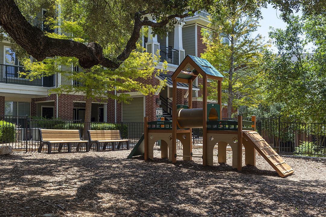 a playground with a swing and a slide in front of a building