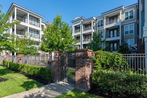 A row of apartment buildings with a metal fence in front.