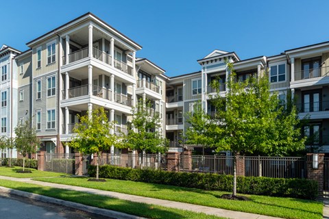 A row of apartment buildings with trees in front.